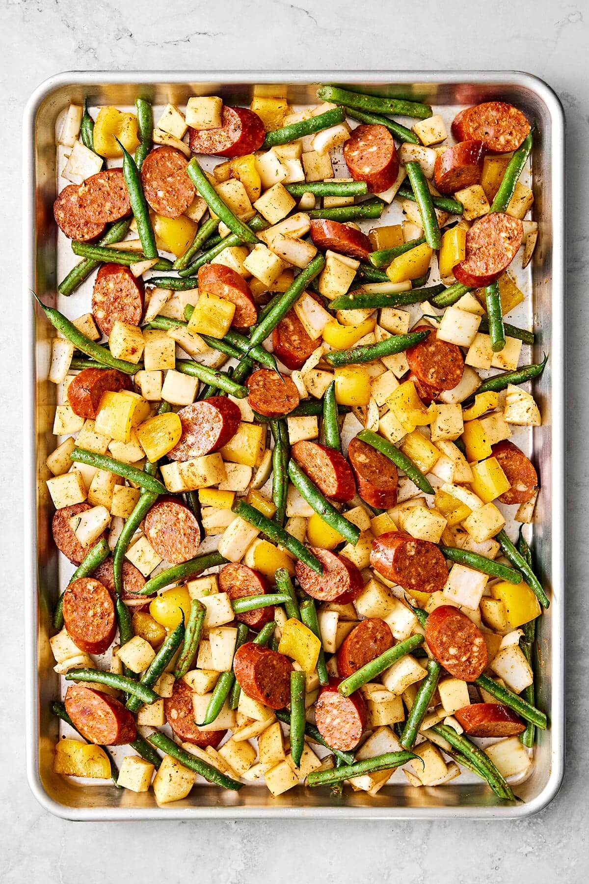 A sheet pan filled with sausage, potatoes, and beans.